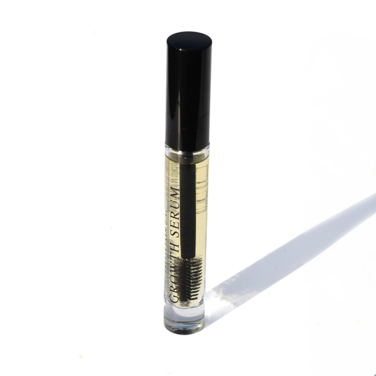 Eyelash + Eyebrow Growth Serum tube with a black cap and pale cream label, standing upright on a white background.